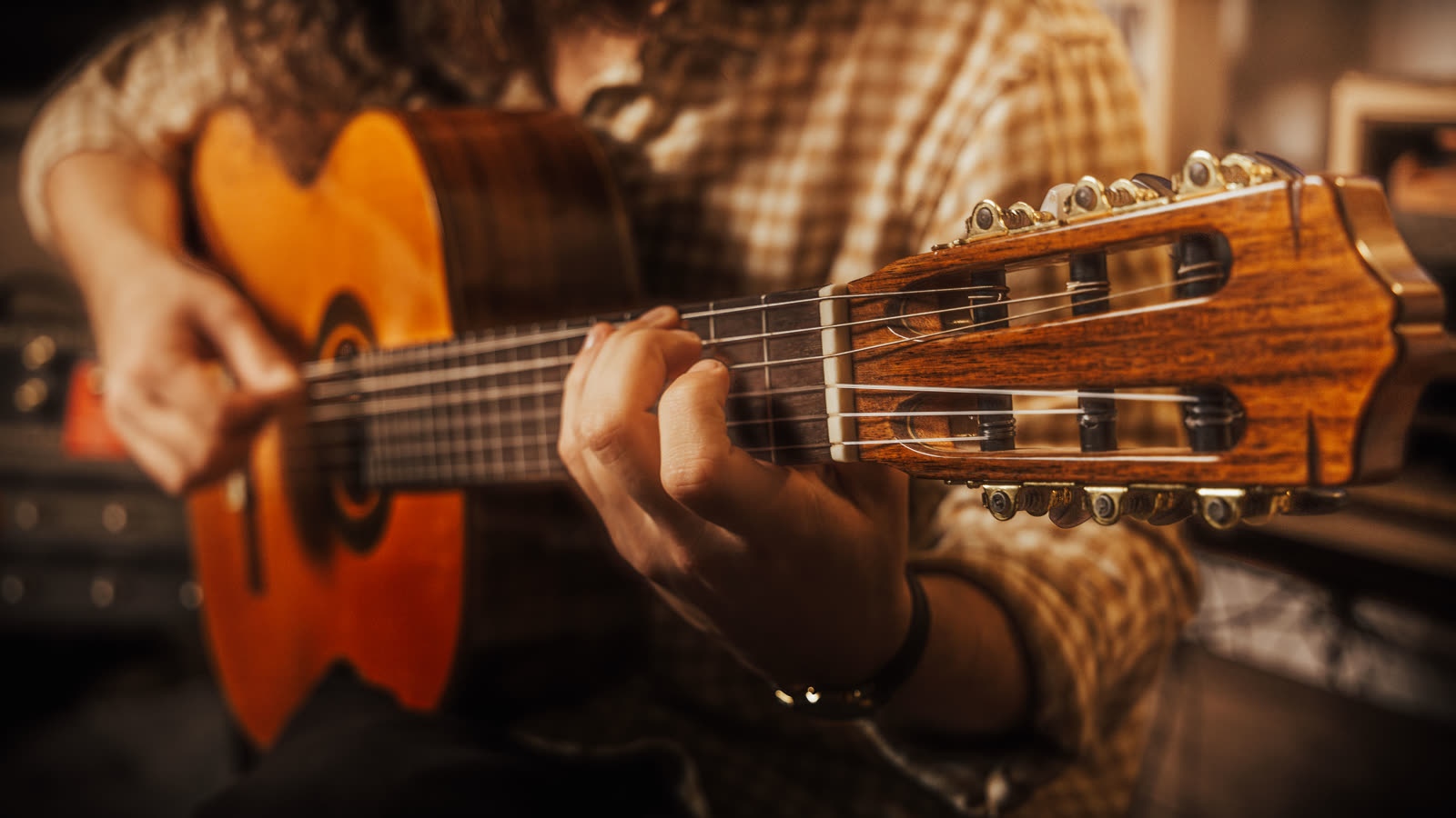 Hands on a classical guitar in warm light
