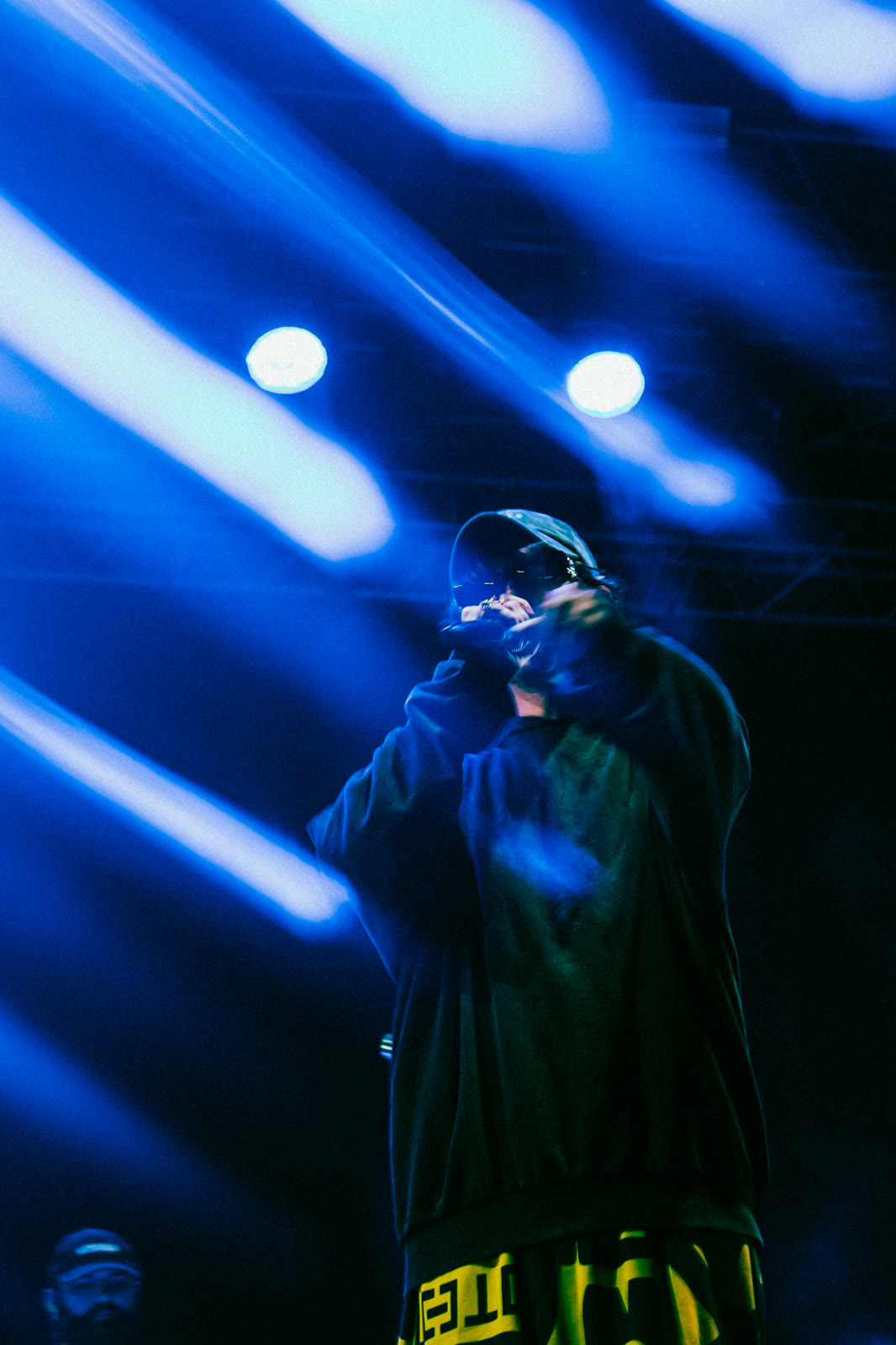 Hooded figure between blue light beams